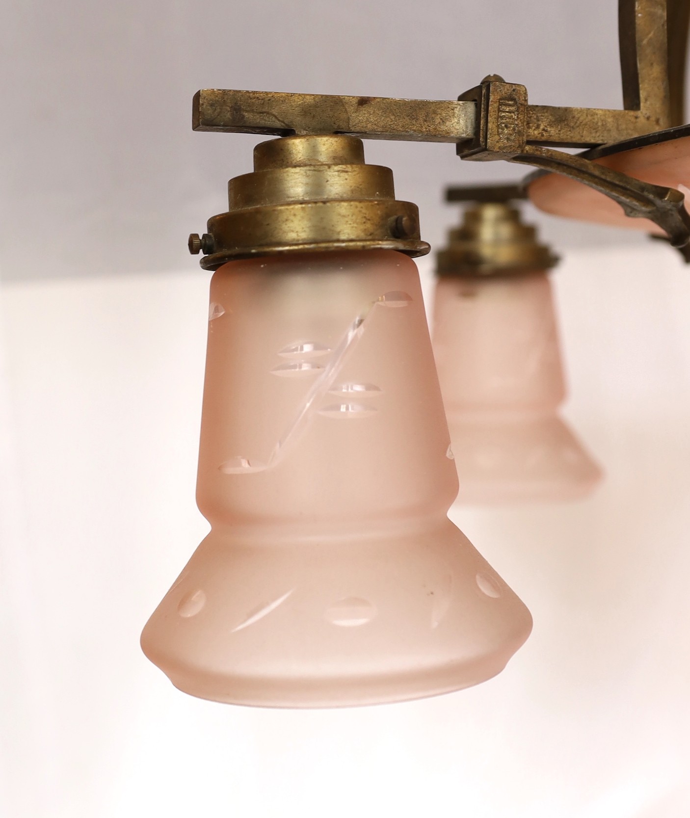 A 1920s-30s German bronze and frosted peach glass five light chandelier of stylish design with geometric cut decoration, drop 75cm. width 70cm